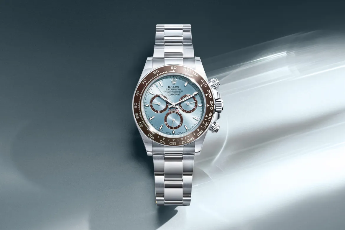 rolex-cosmograph-daytona-cover-m126506-0001-portrait Stainless steel Rolex chronograph with light blue dial and brown bezel, banded bracelet displayed on a muted background
