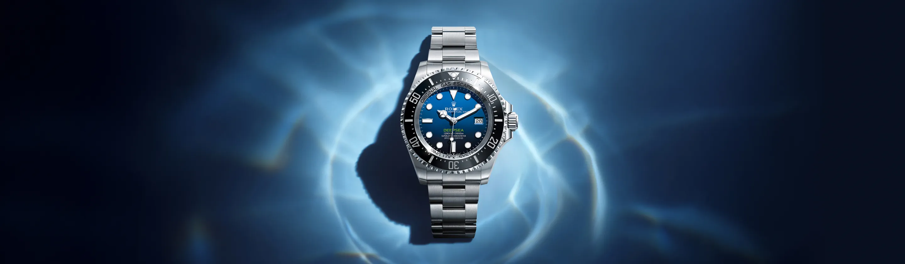 rolex-deepsea-cover-m136660-0005-landscape Stainless steel Rolex dive watch with blue gradient dial and date window, centered against a blue watery background.