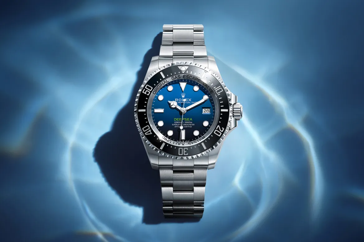 rolex-deepsea-cover-m136660-0005-portrait Rolex Deepsea dive watch with blue dial and stainless steel bracelet against a blue water backdrop.