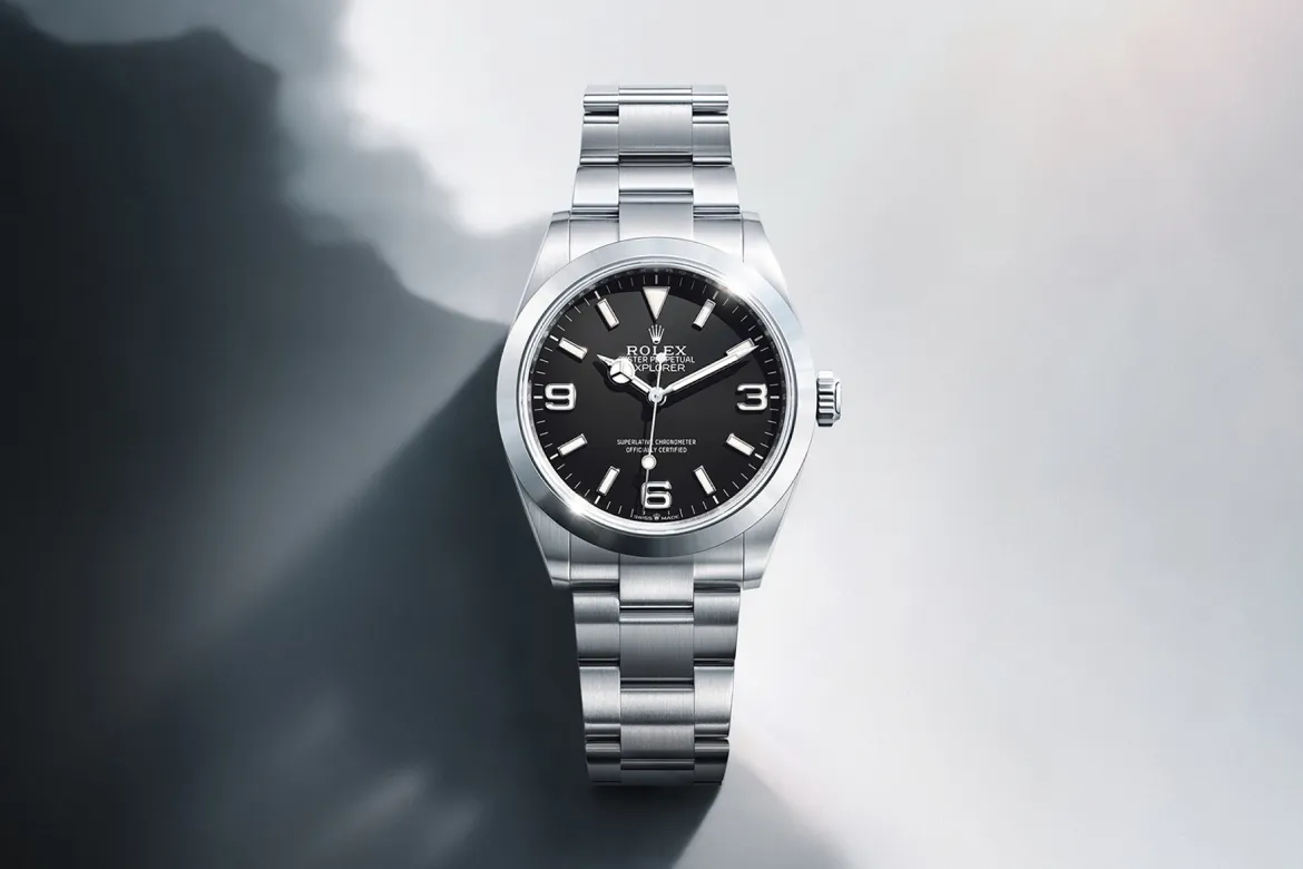 rolex-explorer-cover-m224270-0001-portrait Stainless steel Rolex Explorer watch with black dial, positioned diagonally on a light gradient background.