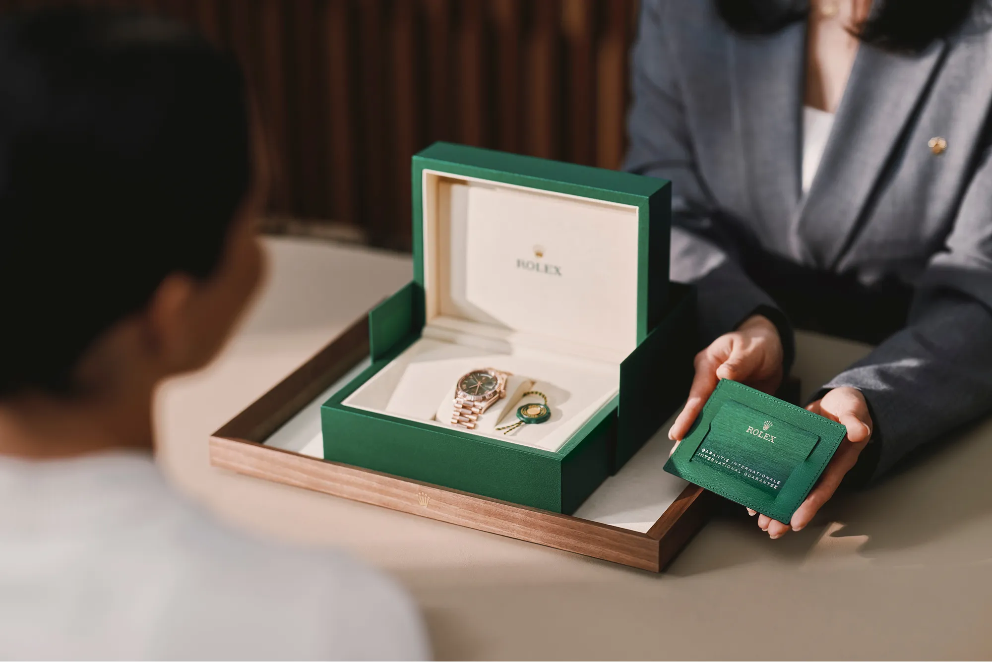 rolex-our-rolex-services | Brela Open Rolex presentation box displaying a gold Rolex watch with green packaging and accompanying accessories on a table. | Brela