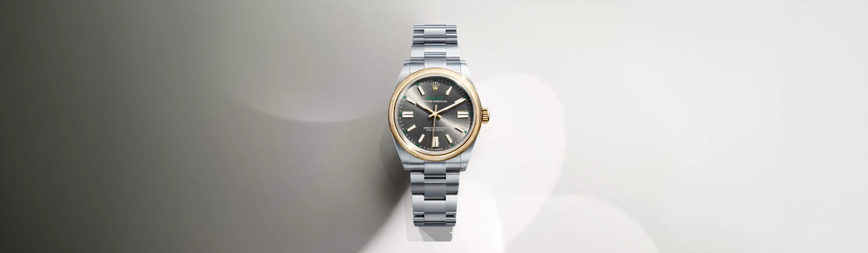 rolex-oyster-perpetual-cover-m134303-0001-landscape Silver and gold Rolex watch with a metal link bracelet on a neutral gradient background, front and center focus.