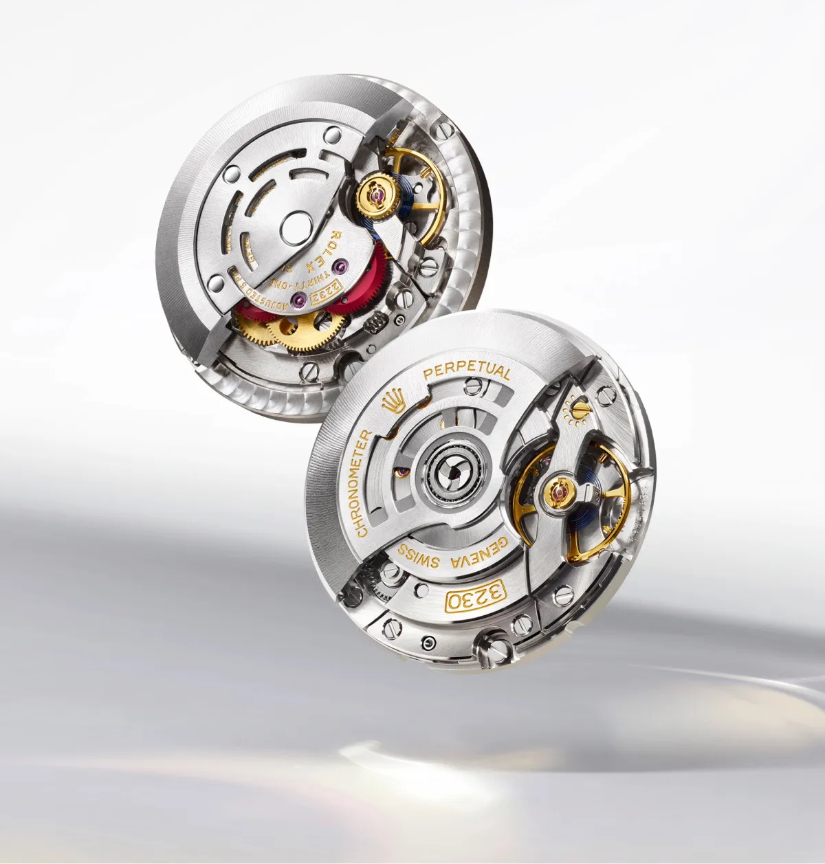 rolex-oyster-perpetual-movement-2232-landscape Two silver mechanical watch movements with gold gears and visible components, labeled Perpetual and Genève Swiss.