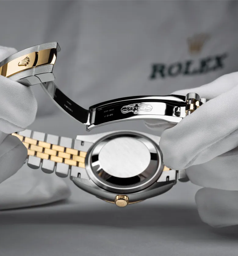 rolex-servicing-2301_rolex_sav_retailers_175_controle-final_fermoir_v2-portrait | Brela Two-tone Rolex watch with gold and silver bracelet being opened to display the clasp and case back. | Brela