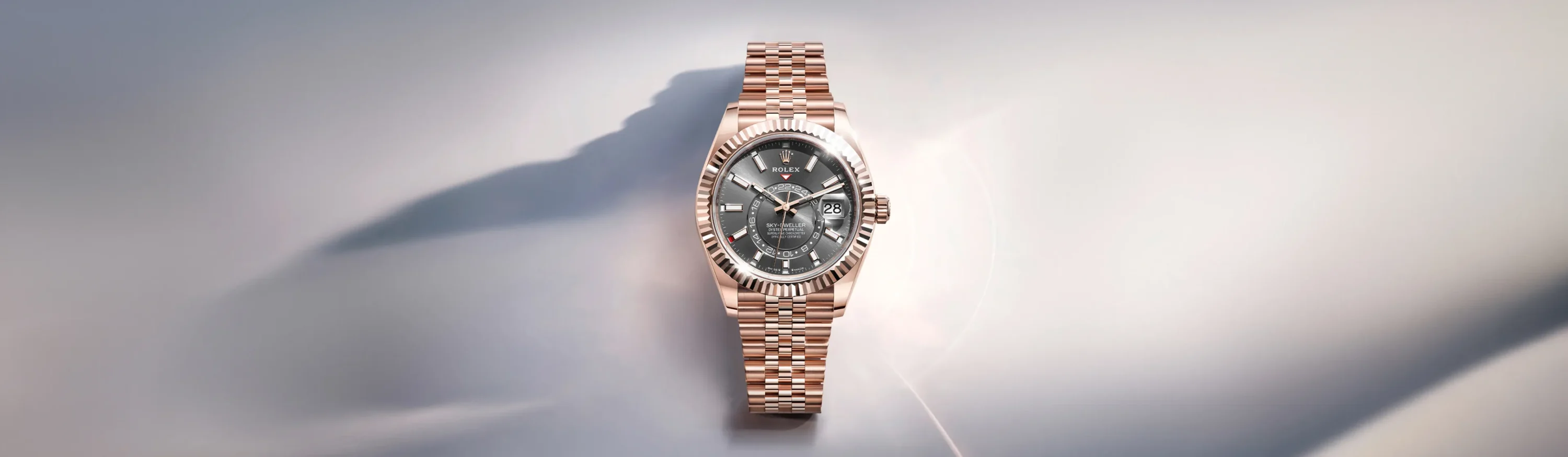 Rose gold Rolex watch with a fluted bezel and grey dial on a soft gradient backdrop.