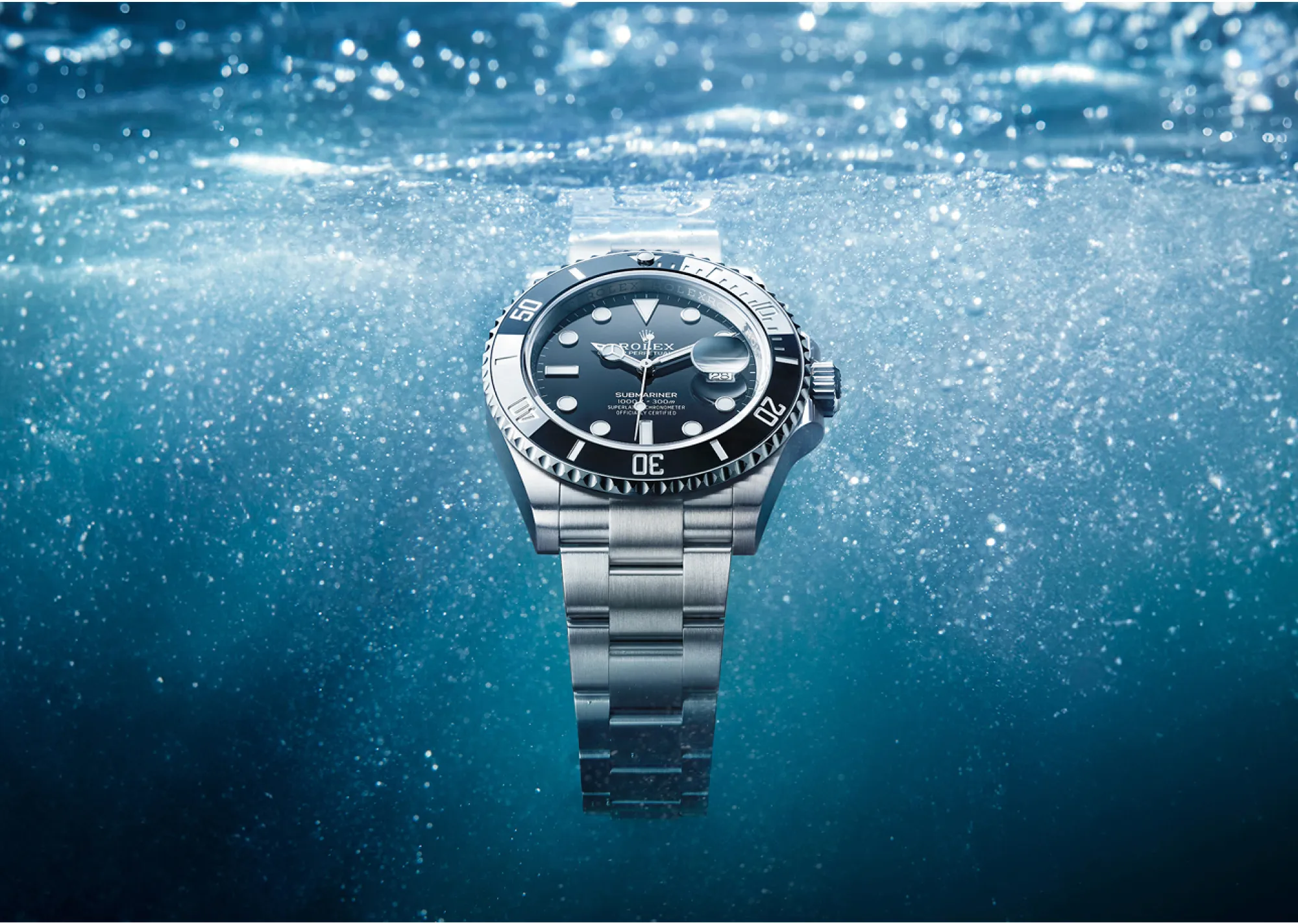 Stainless steel Rolex Submariner watch submerged underwater with bubbles around it.