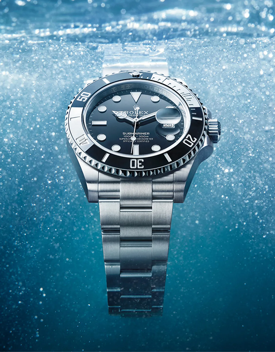 Silver Rolex Submariner wristwatch underwater with bubbles surrounding it.