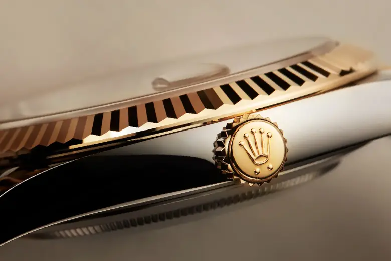 rolex-watches-m126333-0010_1606jva_006-portrait Close-up of a gold Rolex crown on the side of a luxury watch, showing the fluted bezel and polished metal finish.