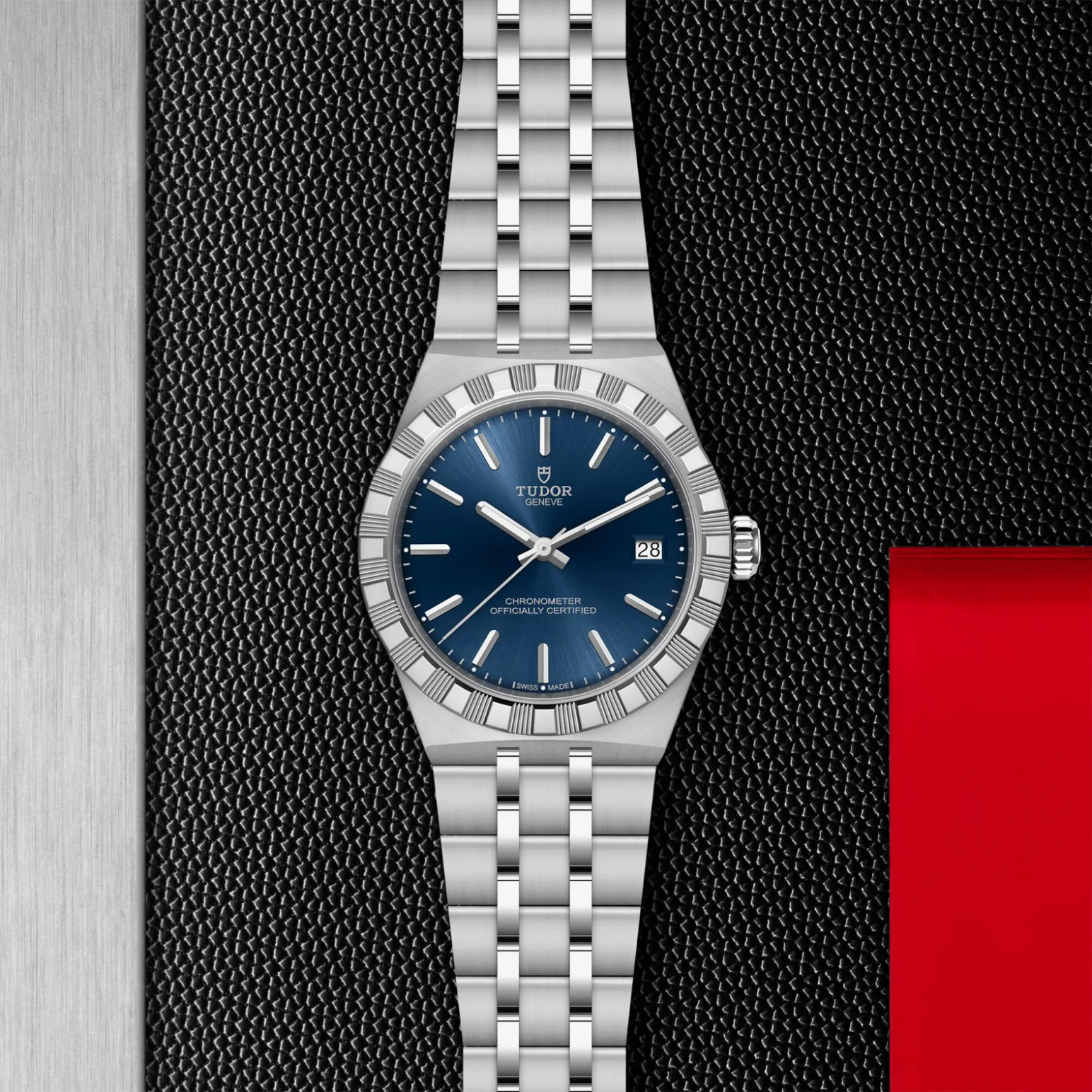 m2836c1a0-0102in_store_flat_lay | Brela Tudor wristwatch with a blue dial and date display on a textured black background. | Brela