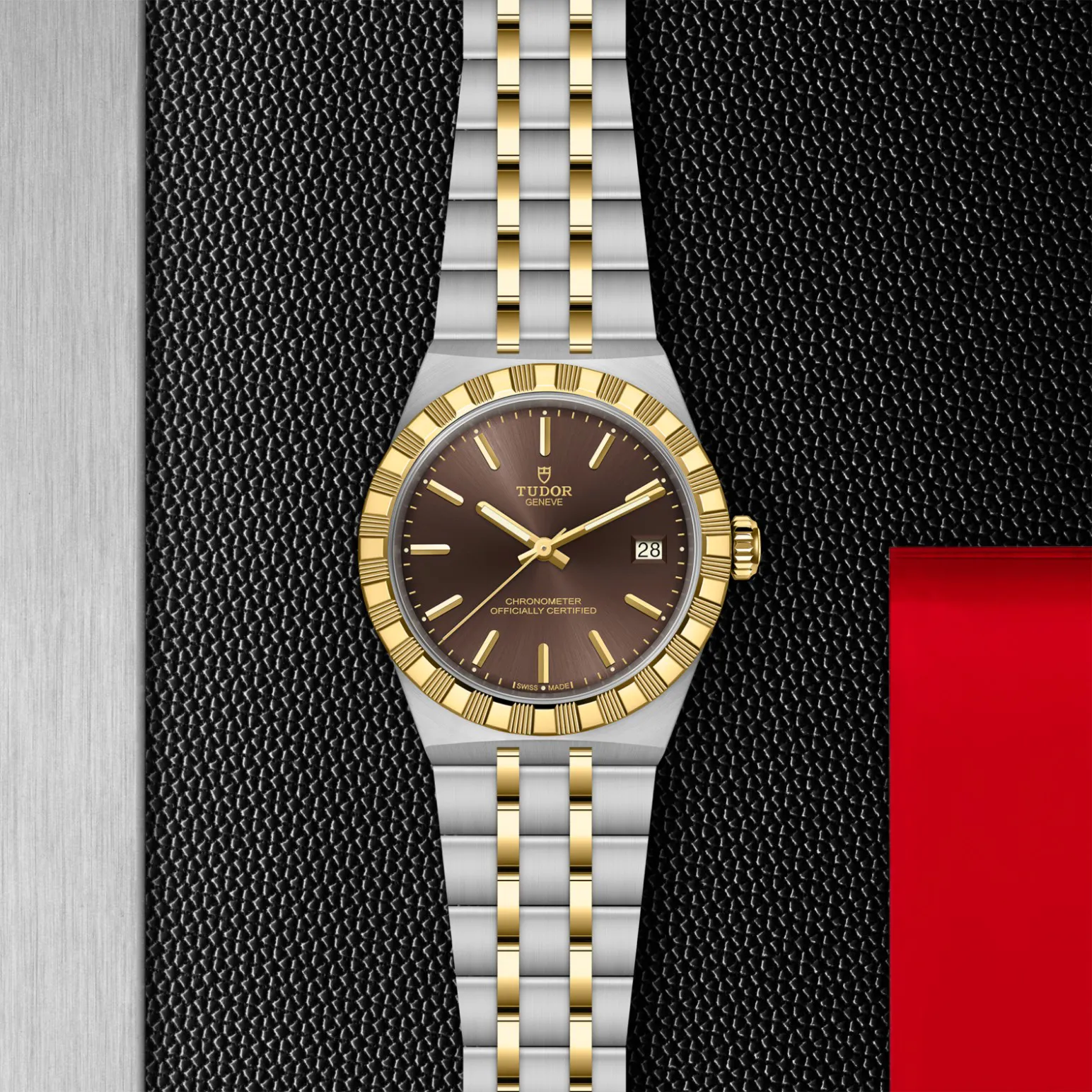 m2836c1a3-0001in_store_flat_lay | Brela Two-tone gold and steel Tudor wristwatch on a textured black backdrop, showing date window at 3 o'clock. | Brela