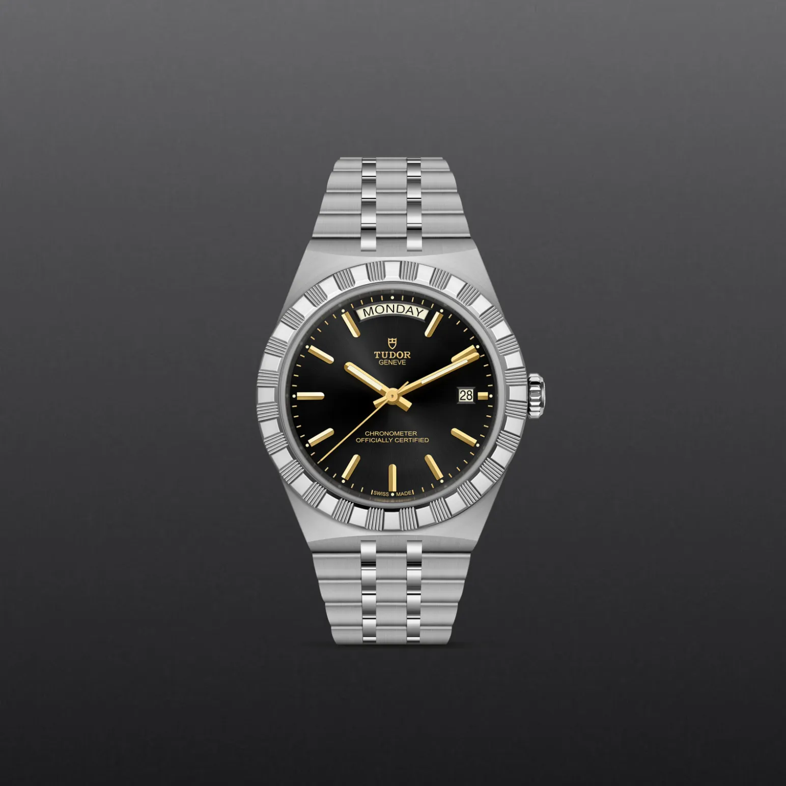 m2840d1a0-0001-upright_watch_grey_background-model_page_only_standard_size | Brela Tudor stainless steel wristwatch with a black dial, gold hands and markers, day-date display, and silver bracelet against a gray background. | Brela
