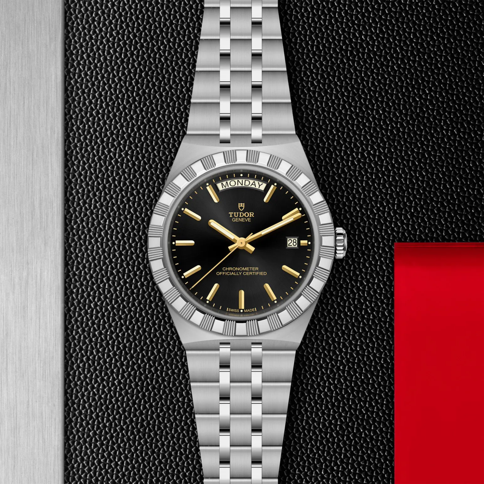 m2840d1a0-0001in_store_flat_lay | Brela Tudor Genève chronometer watch with black dial, gold hands, date window at 3, and day display at top reading Monday | Brela