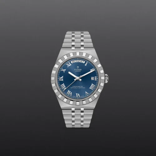 Tudor Genève wristwatch with blue dial, silver Roman numeral hour markers, and stainless steel bracelet showing a date window at 3 o'clock.