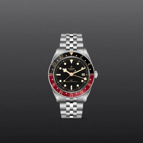 Tudor GMT wristwatch with a black dial, red-and-black bezel, and a stainless steel bracelet showing a date window at 3 o'clock